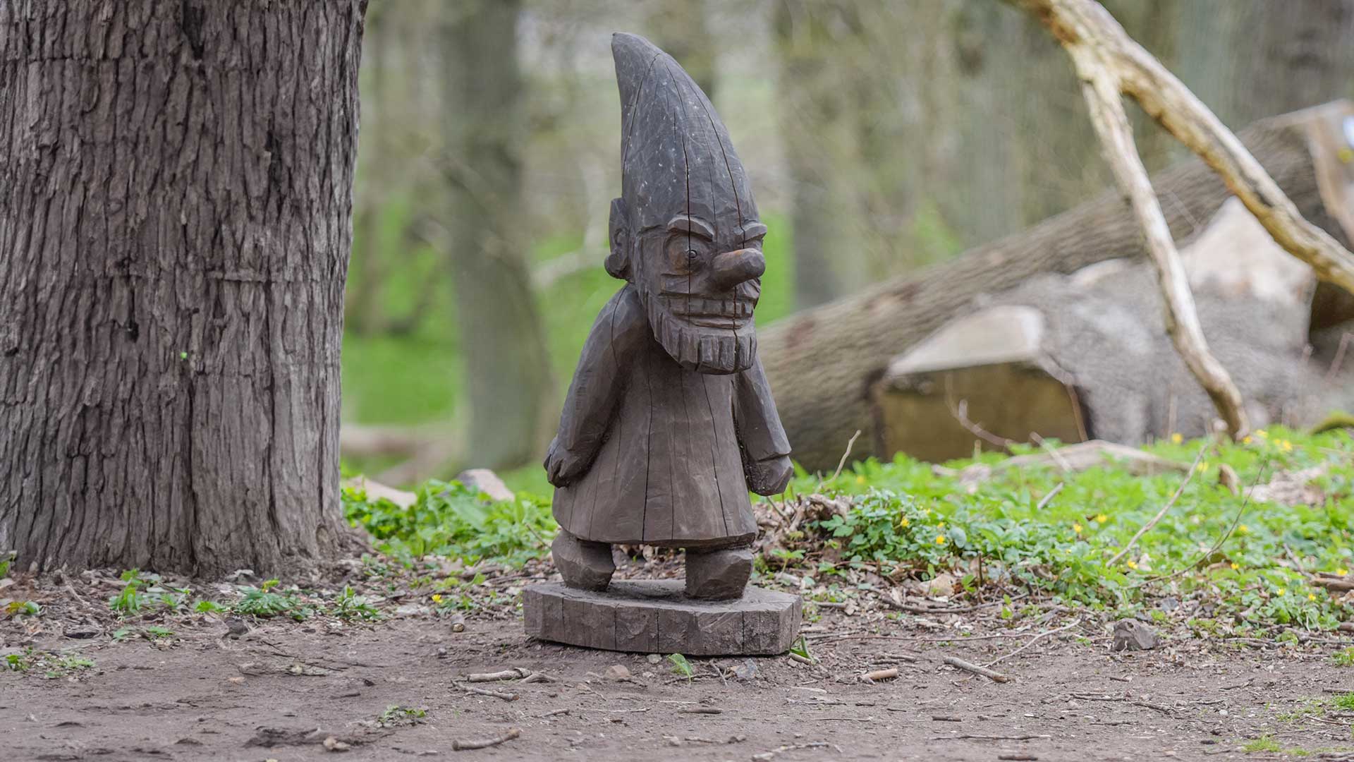 En träskulptur av en vätte med spetsig luva i skogen på Norra Lingenäset.