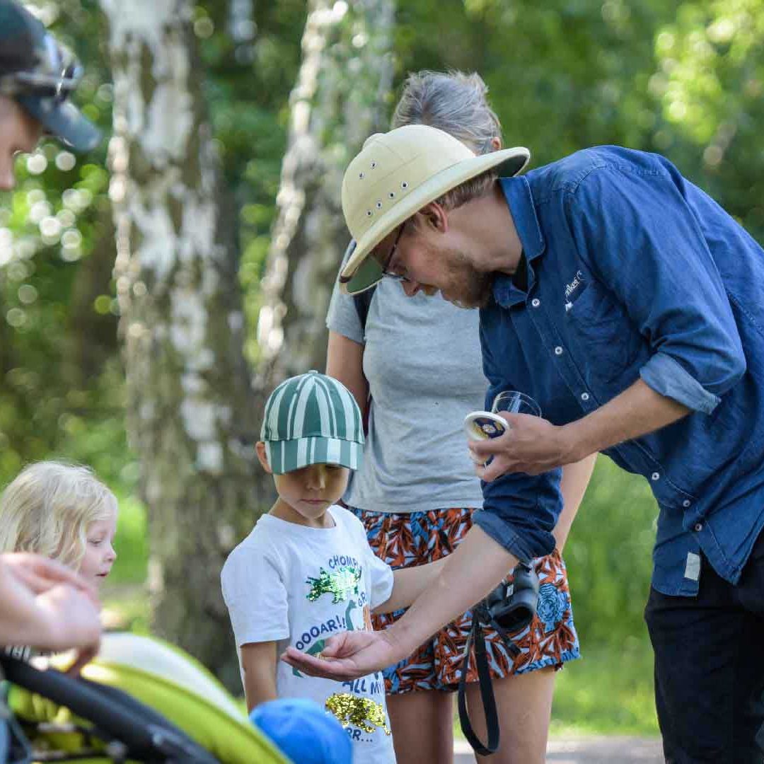 En naturvägledare i safarihatt visar något i handen för barn och vuxna. Foto Jennie Ahlqvist