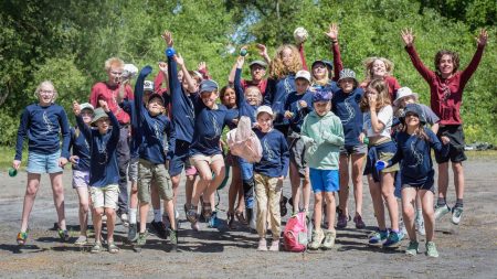 En stor grupp barn i blå tröjor hoppas med armarna upp i luften. Foto Jennie Ahlqvist