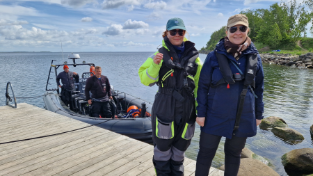 Två personer står på en brygga med en båt i bakgrunden. Foto: Abigail Sykes
