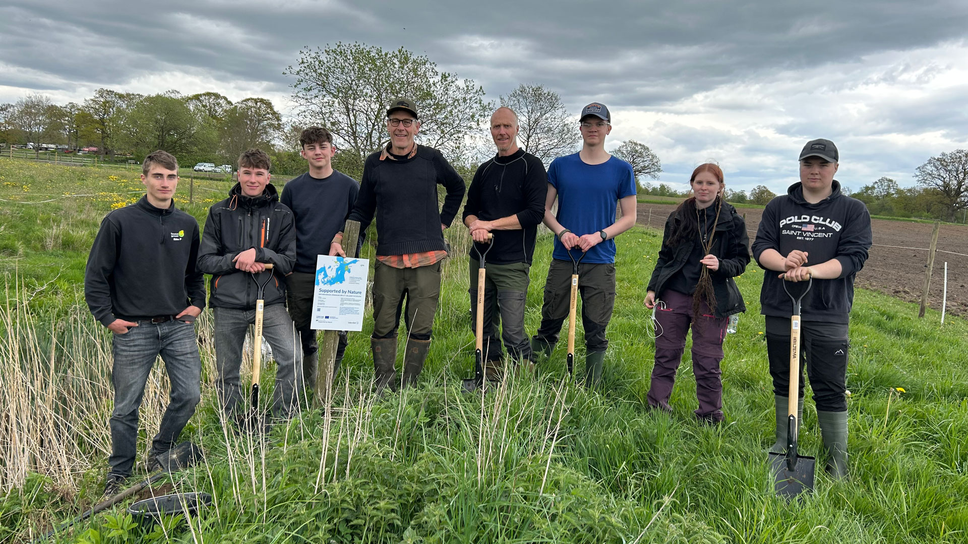 Elever planterar träd vid Mjöån i projektet Supported by Nature