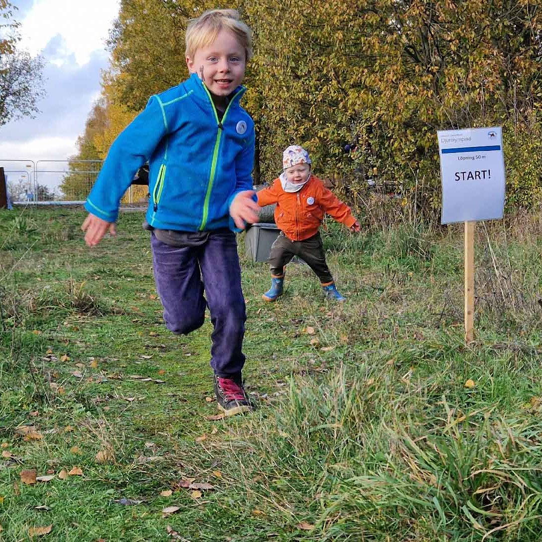 olympiad Två barn springer i gräset. Foto Biosfärkontoret